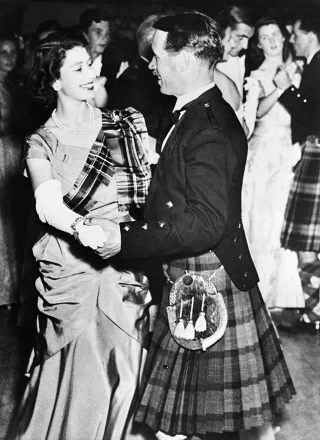 Princess Elizabeth of York, future Queen Elizabeth II, wearing a gown of lime green with a royal stuart tartan sash, dances with David Bogle at the Aboyne Ball, on September 9, 1949 during the Royal couple’s holidays in Scotland. (Photo by INTERCONTINENTALE / AFP) (Photo by -/INTERCONTINENTALE/AFP via Getty Images)