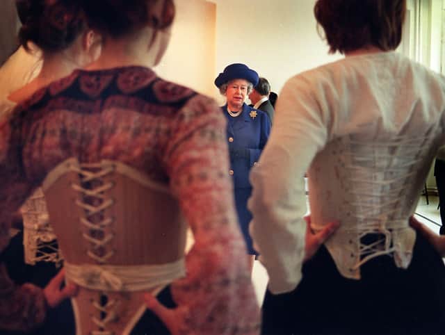 Queen Elizabeth II admires costumes worn by students from the drama school RADA, ahead of their performance of Oklahoma at the Lyceum Theatre