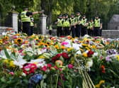 Police officers arrive at the gates of Balmoral in Scotland where flowers and tributes have been laid by members of the public following the death of Queen Elizabeth II. The Queen's coffin will be transported on a six-hour journey from Balmoral to the Palace of Holyroodhouse in Edinburgh, where it will lie at rest. Picture date: Sunday September 11, 2022.