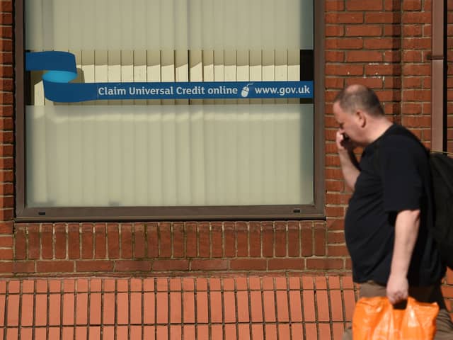 A man walks past a sign with the email address of ‘universal credit’ outside a Job Centre.