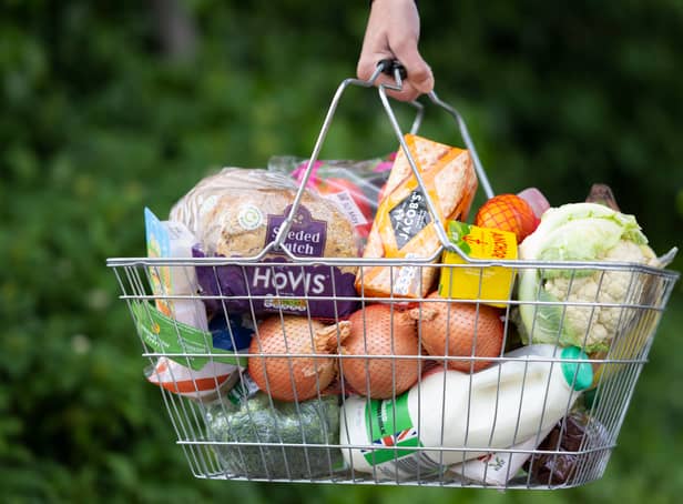 <p>A woman holds a shopping basket of groceries.</p>