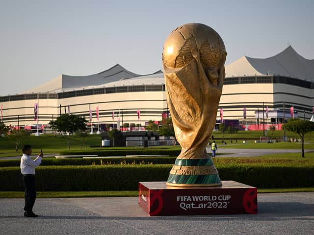 A man takes a picture of a FIFA World Cup trophy replica in front of the Al-Bayt Stadium in al-Khor on November 10, 2022, ahead of the Qatar 2022 FIFA World Cup football tournament. 