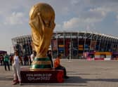 People pose for photos next to a giant replica on the World Cup trophy in front of Stadium 974 on November 18, 2022 in Doha, Qatar