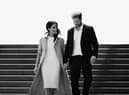 A black and white image of Meghan Markle and Prince Harry walking down a flight of stairs together, hand in hand and smiling (Credit: Netflix) 
