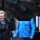 A woman battles to keep control of her umbrella as she walks through a rain shower in Glasgow.