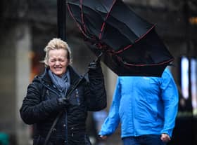 A woman battles to keep control of her umbrella as she walks through a rain shower in Glasgow.