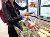 A woman holds a basket of shopping.