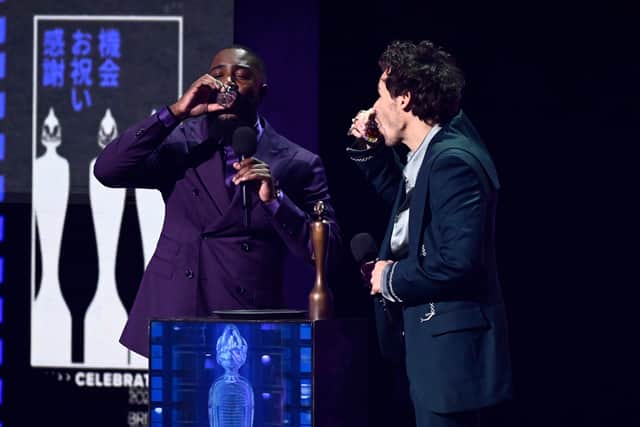 Mo Gilligan and Harry Styles do a shot on stage during The BRIT Awards 