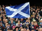 A Scotland fan waves a national flag as they enjoy the pre-match atmosphere prior to a Six Nations Rugby match at Murrayfield Stadium