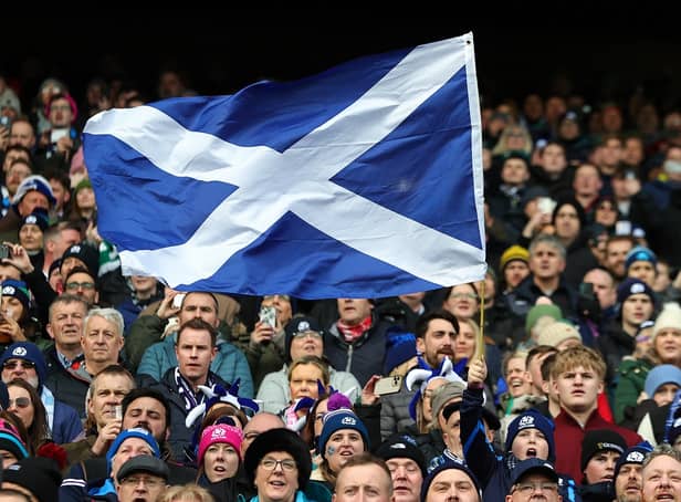 A Scotland fan waves a national flag as they enjoy the pre-match atmosphere prior to a Six Nations Rugby match at Murrayfield Stadium