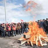 Striking employees gather around a fire outside Gronfreville-l'Orcher refinery on March 24, 2023