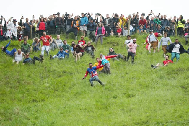 Contestants in the men’s downhill race chase the cheese down the hill in June 2022 in Gloucester, England.