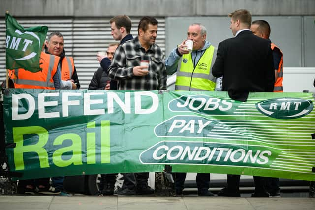 Members of the National Union of Rail, Maritime and Transport Workers (RMT) stand at a picket line outside Euston Station.