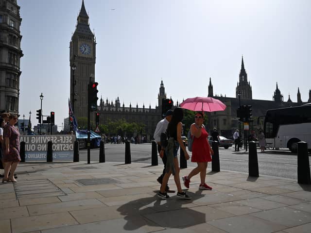 Pedestrians walk in the midday sun past the Palace of Westminster in central London on September 6, 2023 as the late summer heatwave continues.