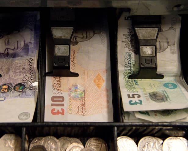 An open cash register containing pound coins and notes is pictured in a convenience store in London