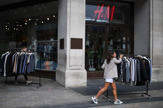 Retail workers move rails of clothes past a H&M store on Oxford Street.