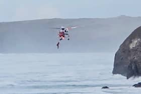 Footage capturing a dog walker being airlifted to safety after falling from a coastal path in Cornwall.  