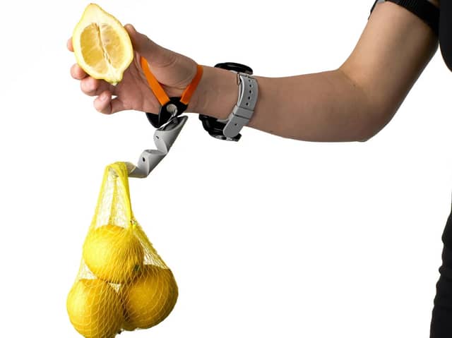 A Third Thumb being used to hold a bag of lemons.