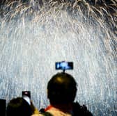 Person taking photo of a firework display. Photo: ANTHONY WALLACE/AFP via Getty Images