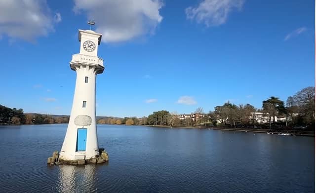 A white clock tower surrounded by water in a serene location