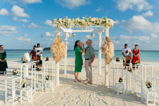Celebrating the ceremony with Champagne and wedding cake under the white floral altar.