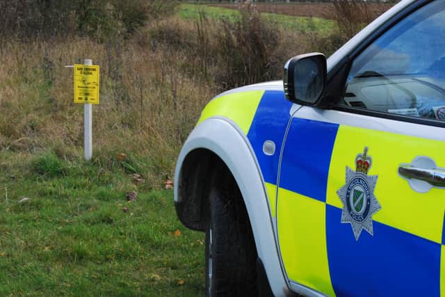 Police out in the countryside parked next to a hare coursing warning sign