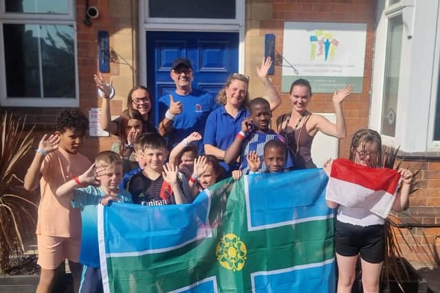 Grzegorz Pacho (pictured centre, back) with Janine Holmes, CEO of the Derbyshire Children's Holiday Centre, with children and volunteers at the centre, holding Derbyshire and Polish flags