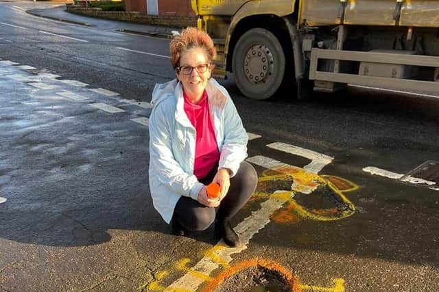 Karan Holland with one of her pothole artworks.