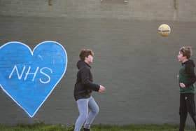 Children play football in the park next to graffiti in support of the NHS. Photo:Justin Setterfield