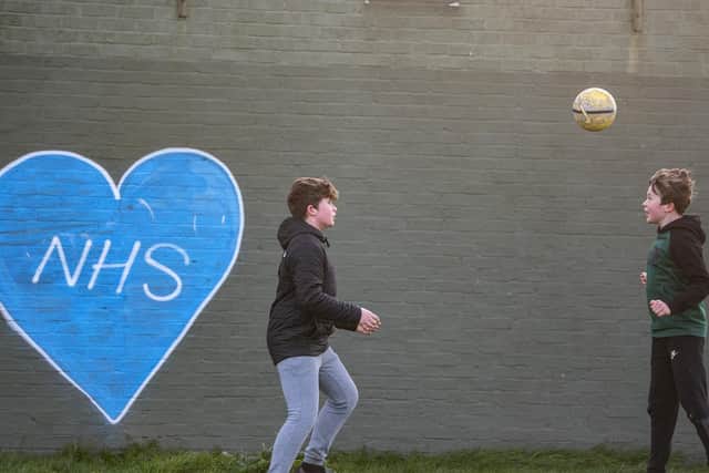 Children play football in the park next to graffiti in support of the NHS. Photo:Justin Setterfield