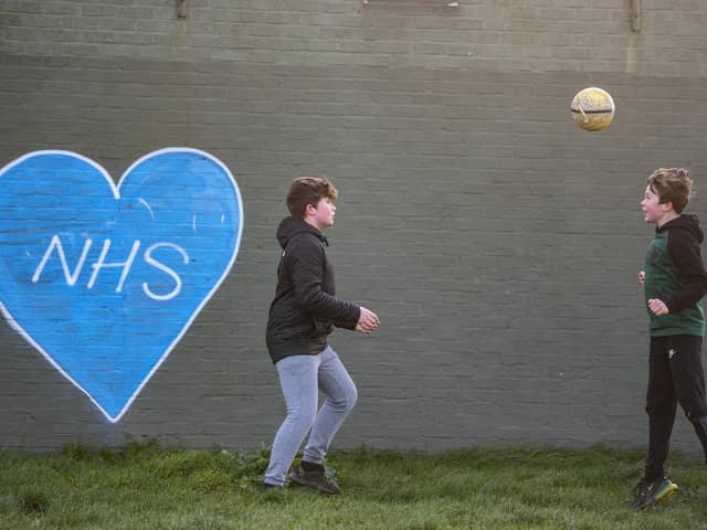 Children play football in the park next to graffiti in support of the NHS. Photo:Justin Setterfield