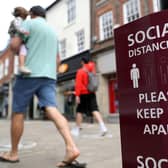 People walk past a social distancing sign, ahead of the re-opening of non-essential retailers in England on June 15. Photo: PA