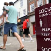 People walk past a social distancing sign, ahead of the re-opening of non-essential retailers in England on June 15. Photo: PA