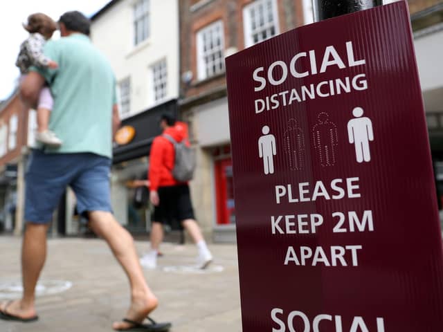 People walk past a social distancing sign, ahead of the re-opening of non-essential retailers in England on June 15. Photo: PA