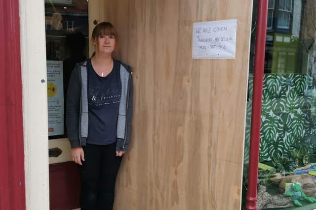 Meg Johnson outside her shop, next to the boarded-up window.