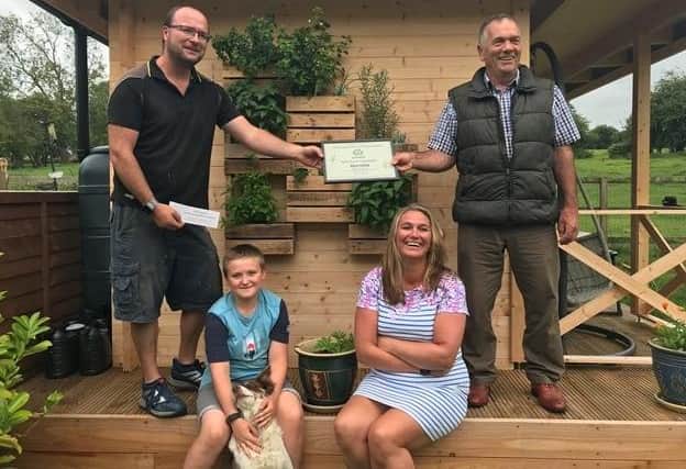 Garden expert John Stirland presents a certificate to Clare Coffey and family for Best Use of Recyclables to Create a Garden at Ropsley. EMN-200724-174704001