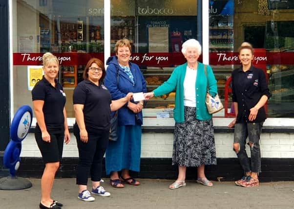 Jacqui Dales, owner of the London Road Bakery, presents the funds to SoLDAS trustees Judith Warnes and Veronica Robinson, watched by members of staff.
