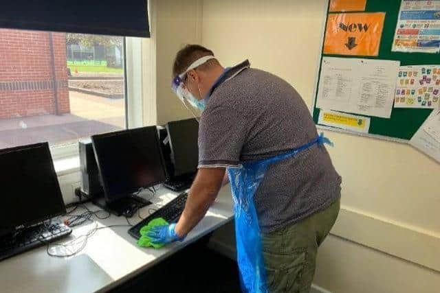 Site manager, Mr Bishell, cleaning school computers following use.