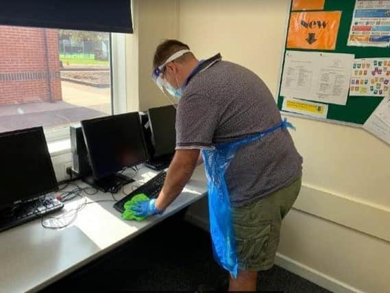 Site manager, Mr Bishell, cleaning school computers following use.
