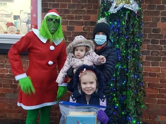 The Grinch -otherwise known as Miss Drury, Class 1 teacher, and pupll Louisa, 5,  hand over cards to Kayleigh Pinnner at Pilgrim