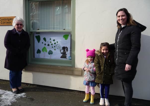 WI member Marian Rippin, left, with granddaughter Sarah Delgado and great-granddaughters Isabella (5) and Emelia (3). Sarah designed the poster. Sitting girl blowing dandelion hearts; each contains a wish the children spoke about with the family.  A photo of the poster was also displayed to their fellow class mates at Ravendale Primary School for them to find out more about the subject.