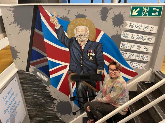 Lucy with the mural that she painted to inspire members of the Elite Fit Gym.