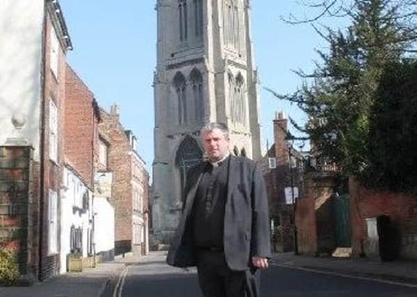 Rev'd Nick Brown, with St James' Church in the background.