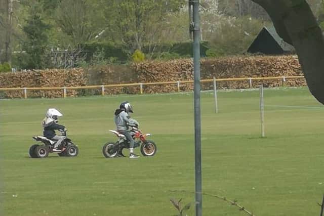 Two individuals have been riding a motobrike and quadbike over the ground at the cricket club.