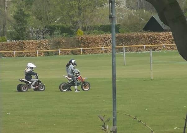 Two individuals have been riding a motobrike and quadbike over the ground at the cricket club.