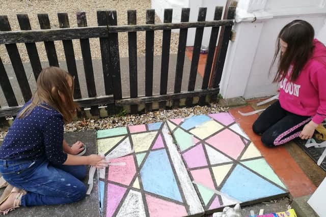 Emily and Caitlin using chalk to decorate a patio area.