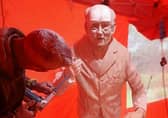 Different stages of the life-sized chainsaw carving of Colonel Tom Moore.
