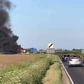 An image of the blazing combine harvester which blocked traffoc on the A153 between North Kyme and Anwick on Wednesday evening. Photo: Geoff Bates EMN-200521-105245001