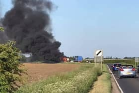 An image of the blazing combine harvester which blocked traffoc on the A153 between North Kyme and Anwick on Wednesday evening. Photo: Geoff Bates EMN-200521-105245001