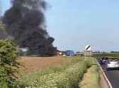 An image of the blazing combine harvester which blocked traffoc on the A153 between North Kyme and Anwick on Wednesday evening. Photo: Geoff Bates EMN-200521-105245001